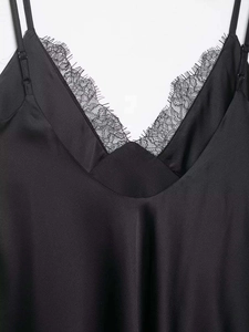 Detailed view of the V-neckline with delicate eyelash lace trim on black satin fabric