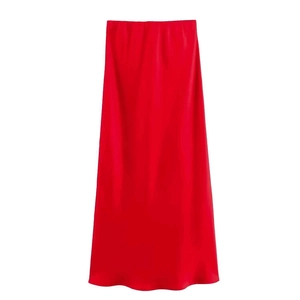 Detail of red satin maxi skirt showing elegant glossy fabric texture and sleek A-line drape