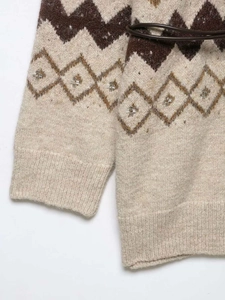 Close-up of vintage jacquard knit sweater with silver beads and brown leather belt
