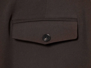 Close-up of flap pocket with round button on dark brown oversized textured suit jacket