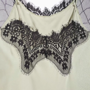 Elegant green satin camisole top with intricate black floral lace trim for women