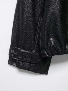 Détail de l'ourlet du blouson aviateur en similicuir avec boucle en métal et texture