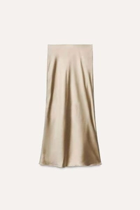 Detailed view of the champagne gold satin midi skirt showing high-gloss texture and draping