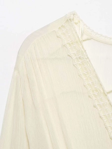 Detail of elegant V-neckline with delicate lace trim on pleated chiffon fabric