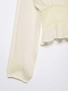 Detail of smocked waist design with geometric embroidery on a beige chiffon blouse