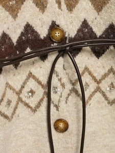 Detail of vintage V-neck knitwear showing geometric patterns and amber buttons with belt