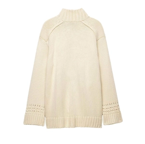 Close-up of cream knit sweater showing high neck ribbing and hollow out sleeve details