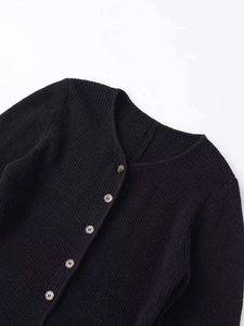 Close-up of black knit cardigan featuring round neck and H-logo buttons in detail