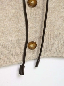 Macro view of oatmeal textured knit fabric with tortoiseshell buttons and dark drawstrings