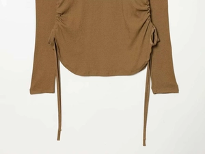 Vue détaillée d'un haut en tricot marron avec cordon de serrage et ourlet incurvé
