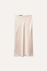 Detailed view of champagne satin midi skirt showing smooth silk texture and waistband