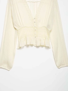 Detail of V-neck lace trim and pleated waist on cream chiffon long sleeve blouse