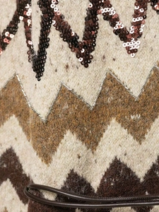 Macro shot of wavy knit sweater texture with dark sequins and silver metal beads