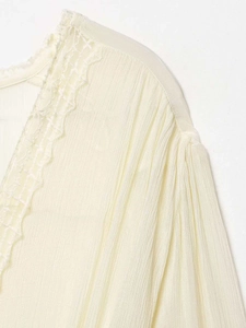Close-up of pleated chiffon top with delicate lace trim and shirred shoulder details