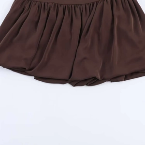 Detail of dark brown satin high waist skirt featuring bubble hem and pleated texture
