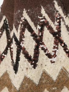 Macro shot of ethnic knitwear detail with sequins, beads, and geometric wavy textures