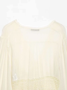 Detail of cream pleated chiffon blouse featuring delicate lace trim and round neckline