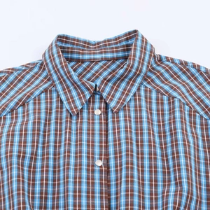Close-up of classic plaid shirt collar with metal snap buttons and blue brown pattern