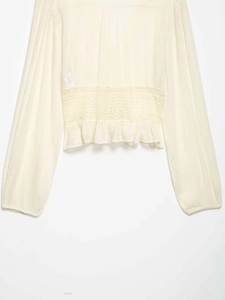 Detailed close-up of cream chiffon blouse with smocked waist and intricate geometric embroidery