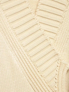 Close-up detail of cream knit cardigan featuring thick ribbed texture and premium stitching