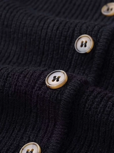Close-up of black ribbed knit cardigan featuring textured fabric and marble-pattern buttons