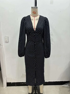 Detail view of the V-neckline and retro polka dot pattern on the long-sleeved midi dress