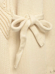 Detailed close-up of cream knit cardigan featuring a textured weave and elegant tie-up bow