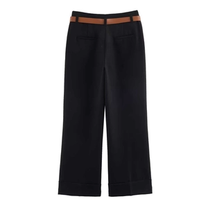 Dettaglio dei pantaloni neri a gamba larga a vita alta con cintura marrone e orlo netto