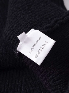 Close-up of the 100% polyester fabric texture and care label on black knit cardigan