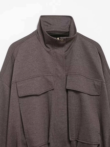Detail of dark plum textured jacket showing high collar and metal button pockets