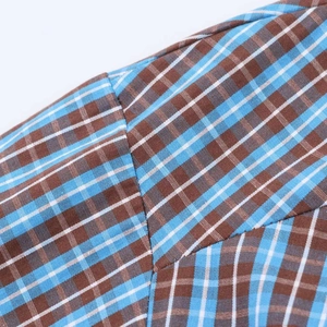 Close-up of blue and brown plaid fabric texture and stitching detail on the dress