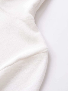Close-up of the delicate knit texture and shoulder seam on a white high-neck sweater