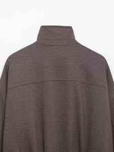 Detail view of dark grey textured jacket showing high collar and shoulder stitching
