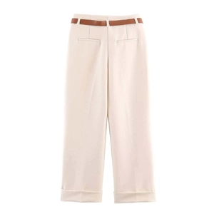 Dettaglio dei pantaloni a gamba larga color crema con cintura marrone e risvolti orlo