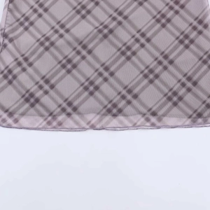 Detalle de la tela con estampado de cuadros grises y marrones con dobladillo cosido a máquina
