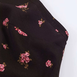 Gros plan de l'imprimé floral sur tissu noir tissé avec coutures sur la robe midi