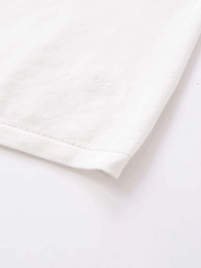 Detail shot of the fine knit texture and high-quality hem stitching on the white sweater