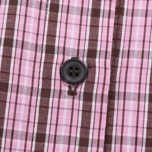 Macro shot of pink and brown plaid fabric texture with a black button detail