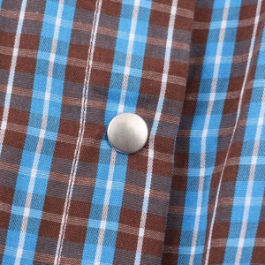 Macro detail of brown and blue checkered fabric with a silver metal snap button