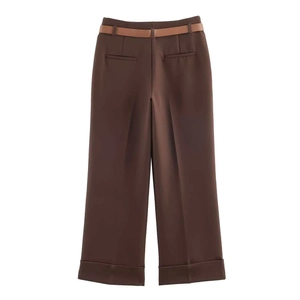 Dettaglio pantaloni marroni a gamba larga con eleganti pieghe in vita e cintura sottile