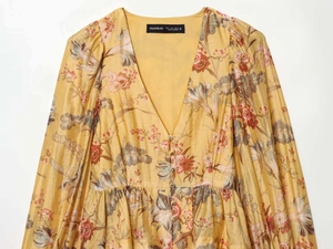 Detail of yellow floral satin dress showing V-neck, vintage print, and small gold buttons