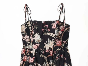 Detailed close-up of floral print dress with tie-up straps and decorative bead trim