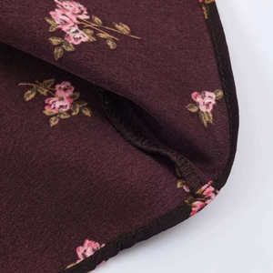 Gros plan sur l'ourlet roulé soigné et l'imprimé floral rose de la robe bordeaux