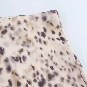 Detailed view of the purple leopard print pattern on smooth beige satin fabric