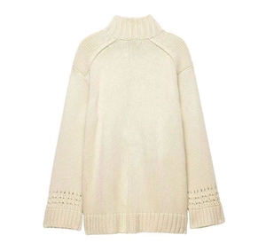 Detail of cream knit cardigan featuring intricate cutout pattern on sleeves and ribbed hem