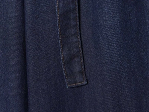 Detailed macro view of deep blue denim fabric with precise yellow double-stitching detail