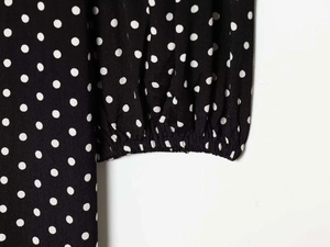 Detail of elastic cuffs and white polka dot pattern on black woven dress fabric