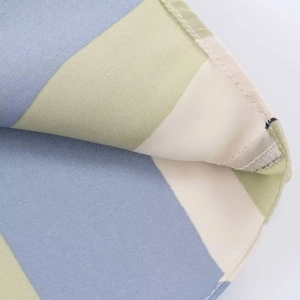 Close-up of sky blue and light green striped satin shirt fabric with neat hem stitching