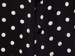 Detailed macro view of a black polka dot dress featuring a fabric-covered button detail