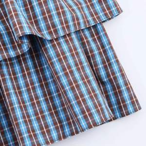 Detail of layered blue and brown checkered fabric on a minimalist summer dress